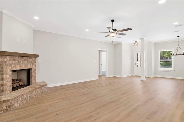 unfurnished living room featuring crown molding, a brick fireplace, light wood-style floors, baseboards, and ceiling fan with notable chandelier