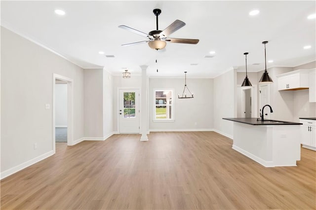 unfurnished living room featuring crown molding, light wood-type flooring, a sink, baseboards, and recessed lighting