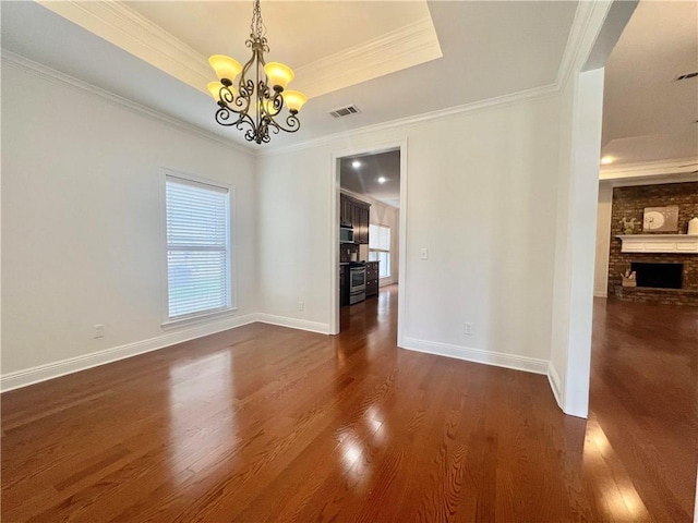 unfurnished dining area with a tray ceiling, dark wood finished floors, and a healthy amount of sunlight