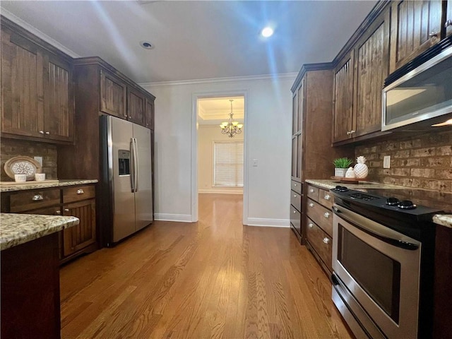 kitchen featuring light wood finished floors, light stone countertops, stainless steel appliances, crown molding, and dark brown cabinets