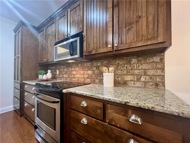 kitchen with light stone countertops, stainless steel appliances, dark wood-type flooring, baseboards, and decorative backsplash