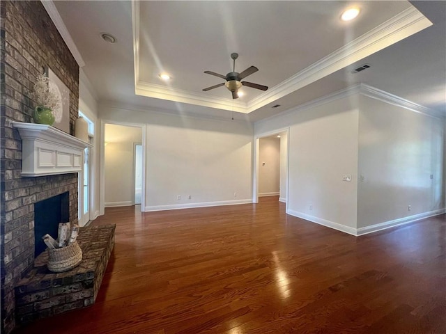 unfurnished living room with a fireplace, visible vents, a raised ceiling, and dark wood-style flooring