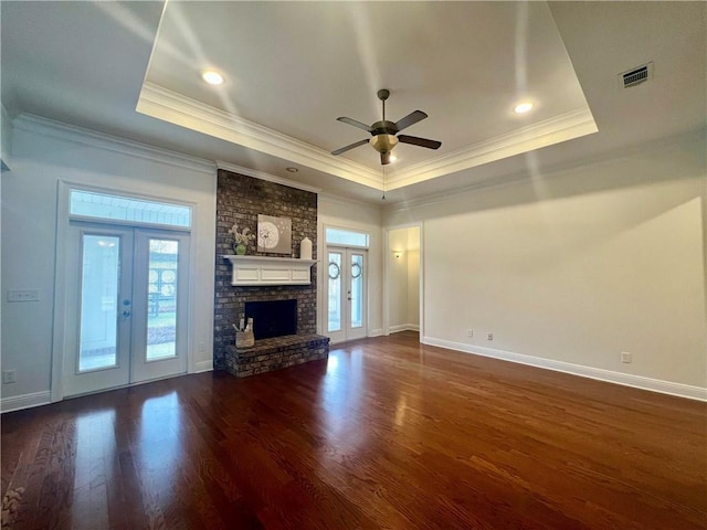 unfurnished living room with a tray ceiling, french doors, visible vents, and a healthy amount of sunlight