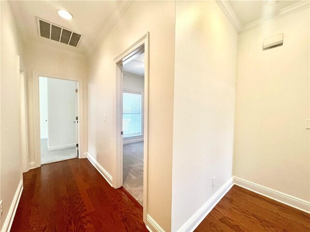 hall featuring baseboards, crown molding, visible vents, and wood finished floors