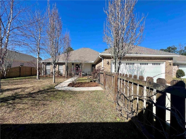 view of front of house with an attached garage, a shingled roof, fence, and a front yard