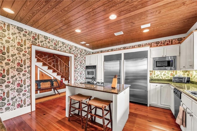 34460 Steelwood Ridge Rd, Loxley, AL 36551 - kitchen featuring built in appliances, wallpapered walls, wood-type flooring, a breakfast bar area, and wooden ceiling