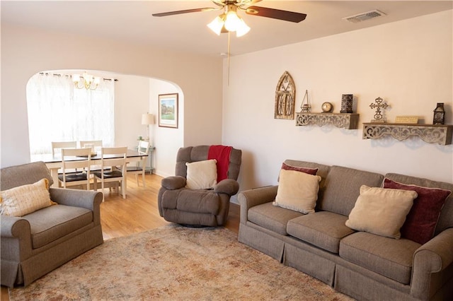 living room with hardwood / wood-style flooring and ceiling fan with notable chandelier