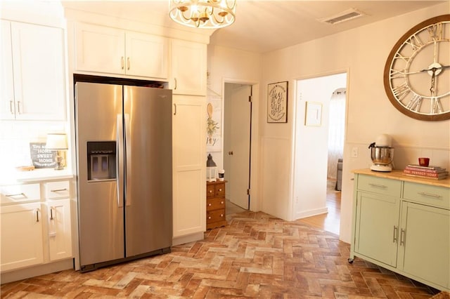 kitchen with white cabinets, decorative backsplash, stainless steel fridge, and green cabinetry