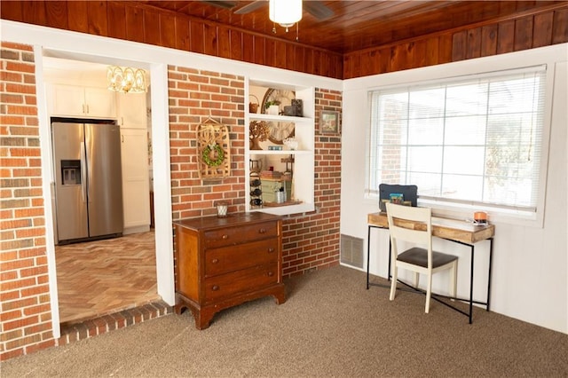 home office featuring light carpet, wooden ceiling, ceiling fan, and brick wall