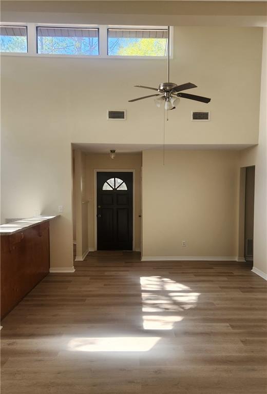 entrance foyer featuring a wealth of natural light, ceiling fan, a towering ceiling, and hardwood / wood-style flooring