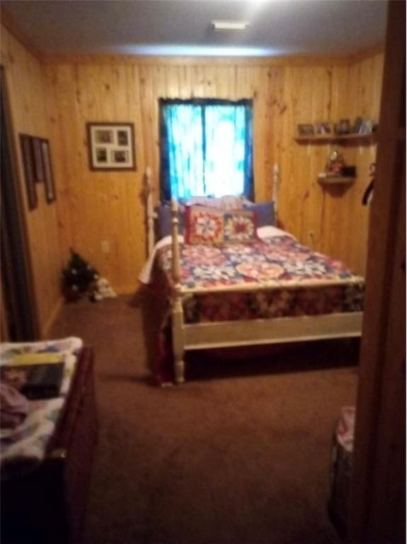 bedroom with wood walls and dark colored carpet