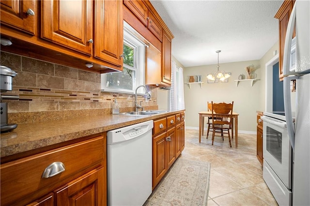 kitchen with tasteful backsplash, white appliances, an inviting chandelier, decorative light fixtures, and sink