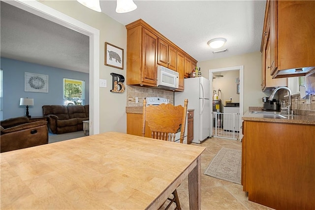 kitchen featuring light tile patterned flooring, sink, white appliances, tasteful backsplash, and a textured ceiling