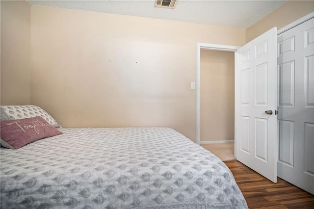 bedroom with a textured ceiling and dark hardwood / wood-style flooring