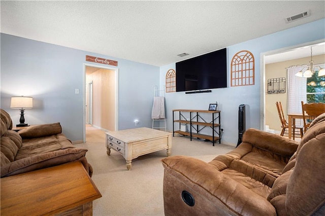 living room with a notable chandelier, a textured ceiling, and light carpet