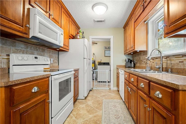 kitchen with a textured ceiling, sink, backsplash, white appliances, and light tile patterned floors