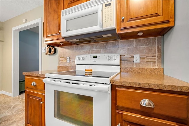 kitchen featuring decorative backsplash, white appliances, and light tile patterned floors