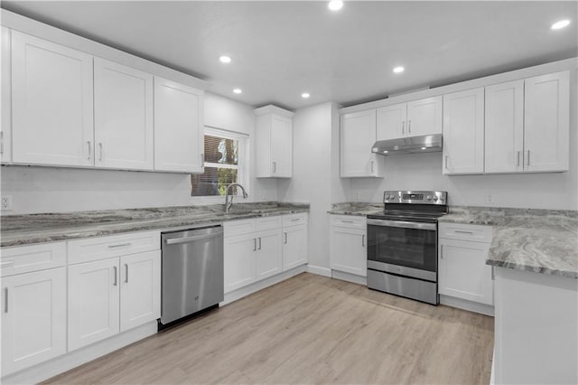 kitchen with under cabinet range hood, a sink, white cabinetry, appliances with stainless steel finishes, and light wood-type flooring