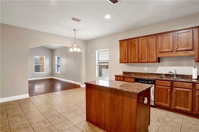 kitchen featuring arched walkways, a kitchen island, a sink, visible vents, and stainless steel dishwasher