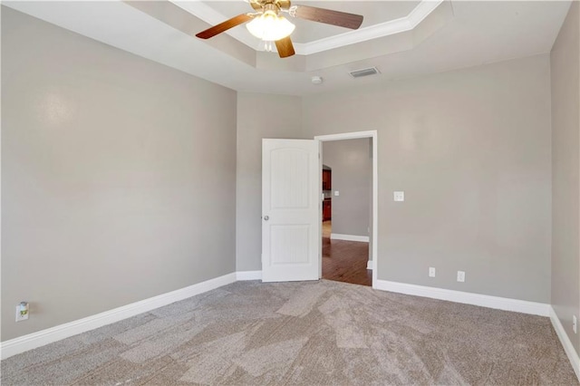 spare room featuring baseboards, visible vents, and a raised ceiling