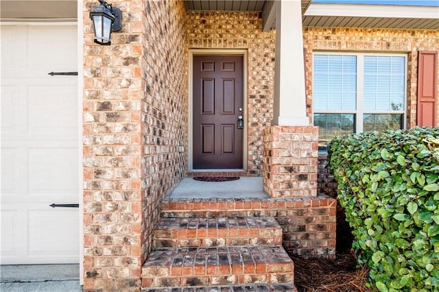 entrance to property featuring a garage and brick siding