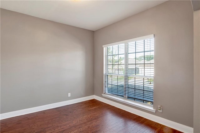 spare room featuring dark wood-style floors and baseboards