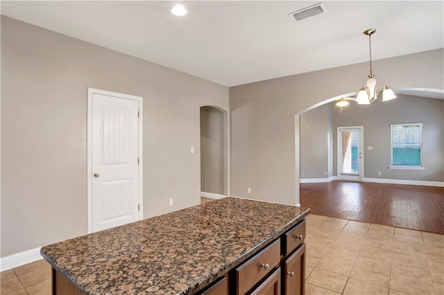 kitchen featuring arched walkways, pendant lighting, visible vents, and baseboards