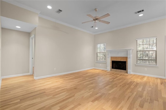 unfurnished living room featuring a tile fireplace, light hardwood / wood-style flooring, ceiling fan, and ornamental molding