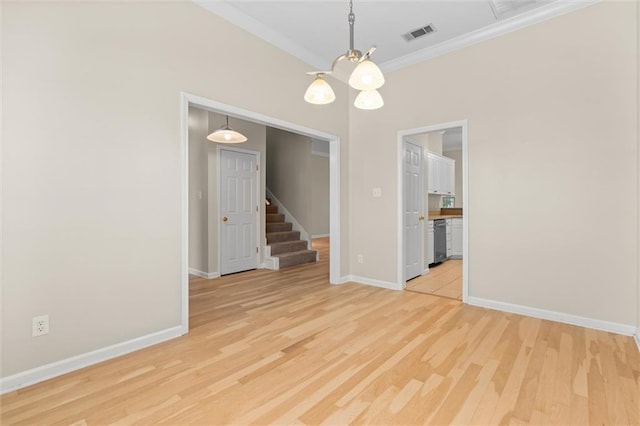 spare room with a chandelier, crown molding, and light hardwood / wood-style floors