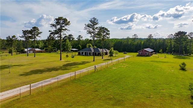 view of yard with a rural view, fence, and a wooded view