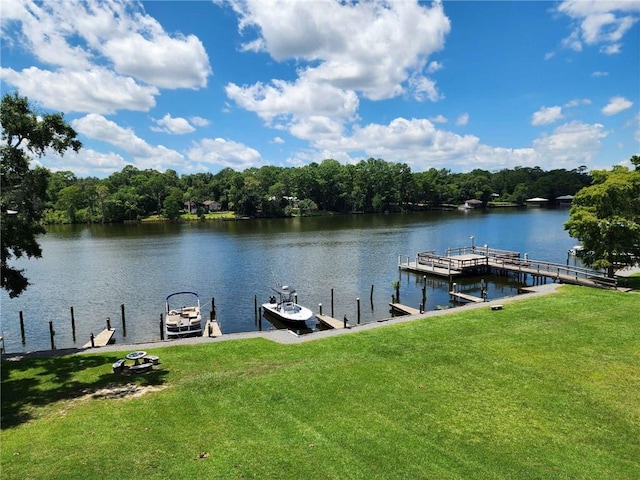 view of dock with a lawn and a water view