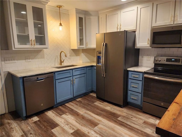 kitchen with pendant lighting, sink, hardwood / wood-style flooring, white cabinetry, and stainless steel appliances