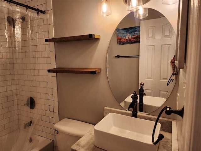 full bathroom with sink, tiled shower / bath combo, and toilet