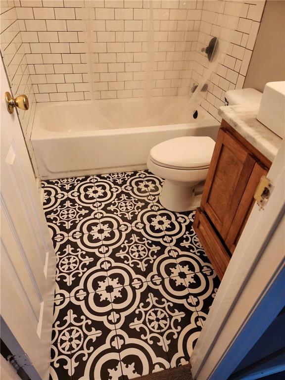 full bathroom featuring tile patterned floors, vanity, tiled shower / bath combo, and toilet