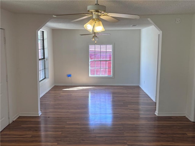 unfurnished room with a textured ceiling, dark hardwood / wood-style flooring, plenty of natural light, and ceiling fan