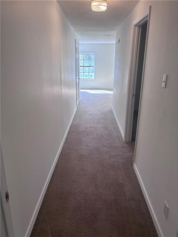 corridor featuring a textured ceiling and carpet floors