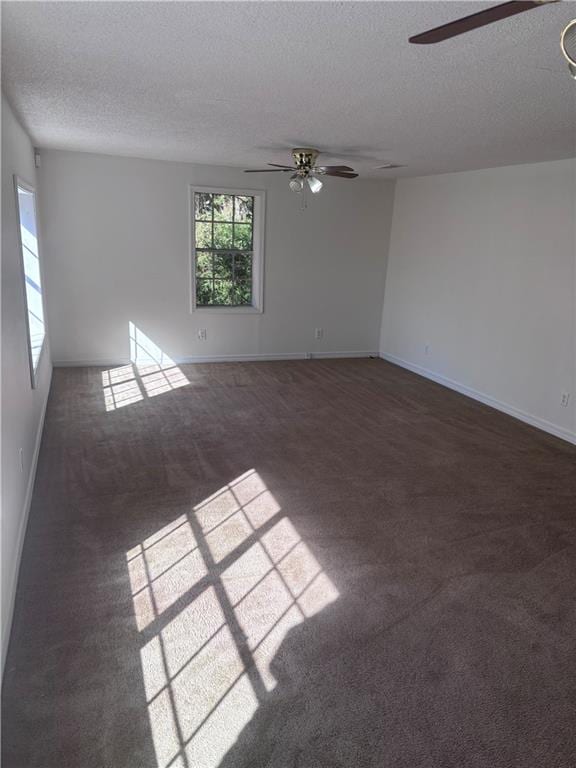 spare room with a textured ceiling and dark carpet