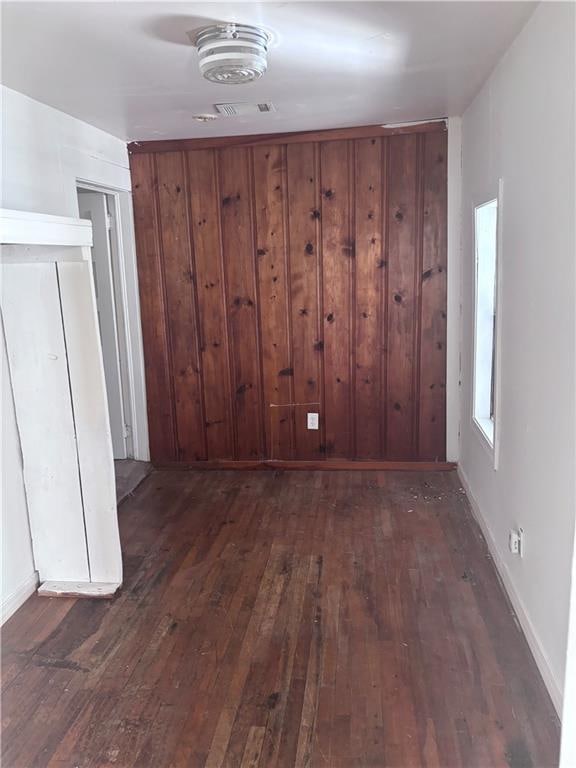 spare room featuring dark hardwood / wood-style floors and wood walls