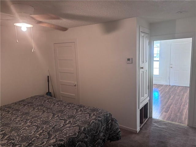 bedroom with dark colored carpet, ceiling fan, and a textured ceiling