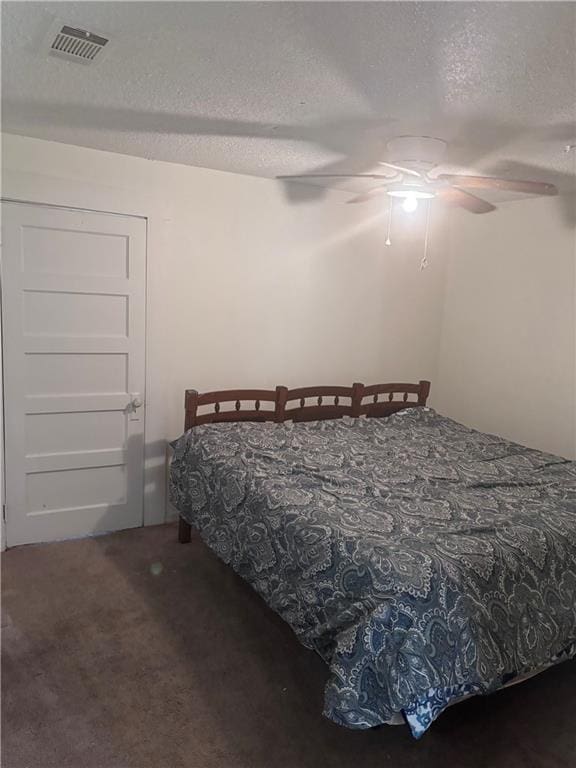 carpeted bedroom featuring ceiling fan and a textured ceiling