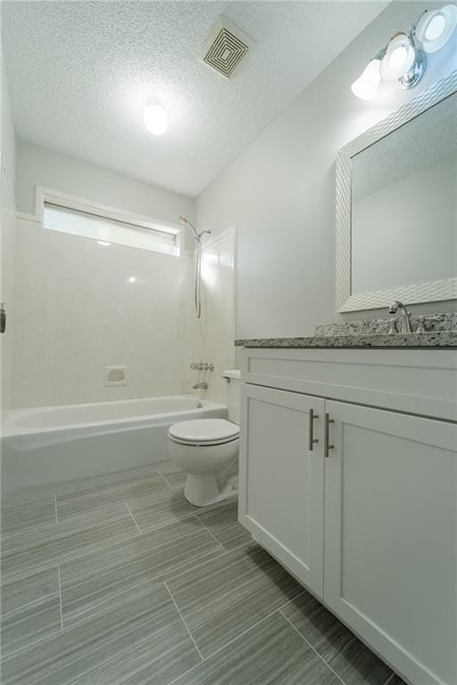 full bathroom featuring toilet, a textured ceiling, vanity, and tub / shower combination