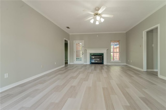 unfurnished living room with crown molding, light wood-type flooring, a high end fireplace, and ceiling fan