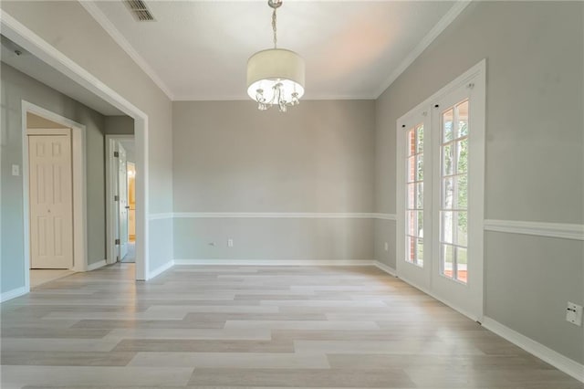 spare room featuring an inviting chandelier, french doors, crown molding, and light wood-type flooring