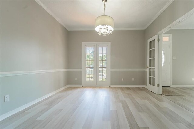 empty room featuring french doors, crown molding, an inviting chandelier, and light wood-type flooring