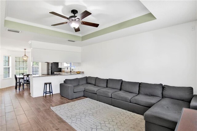 13310 August Dr, Mobile, AL 36695 - living area with ornamental molding, wood finished floors, a ceiling fan, a tray ceiling, and baseboards