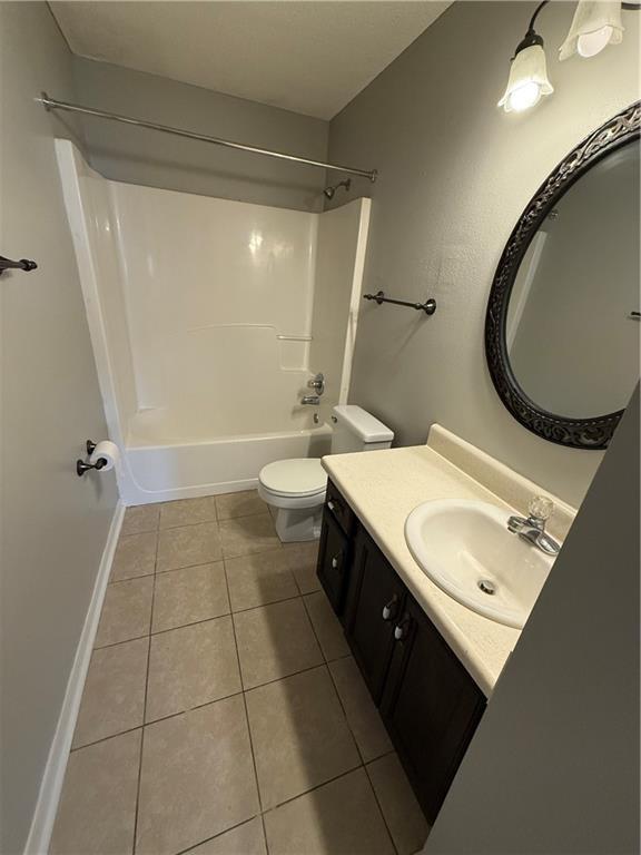 full bath with toilet, shower / washtub combination, tile patterned flooring, baseboards, and vanity