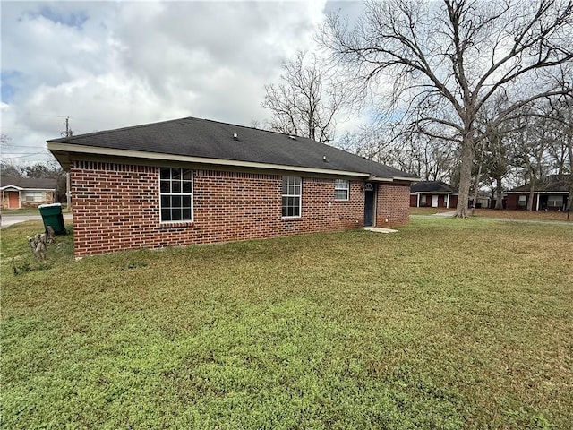 back of property with a yard and brick siding