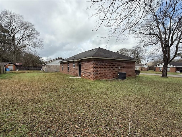 view of side of home with cooling unit, an outbuilding, a lawn, and fence