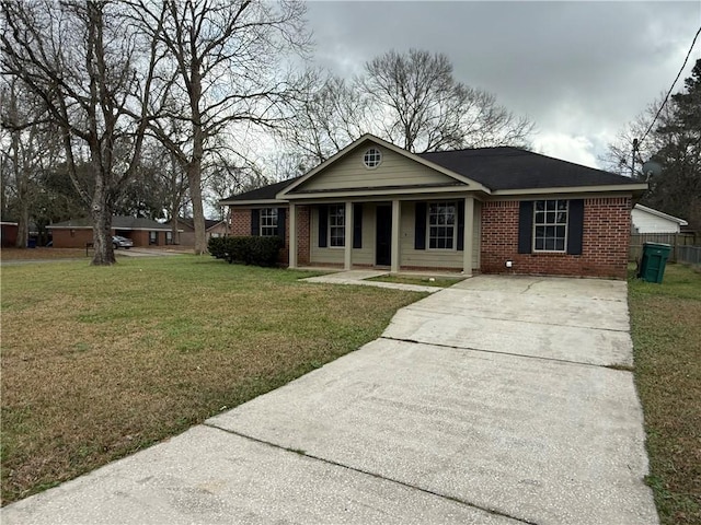 view of front of property with brick siding, driveway, a front yard, and fence