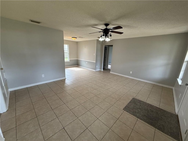 tiled spare room featuring baseboards, visible vents, a textured ceiling, and ceiling fan